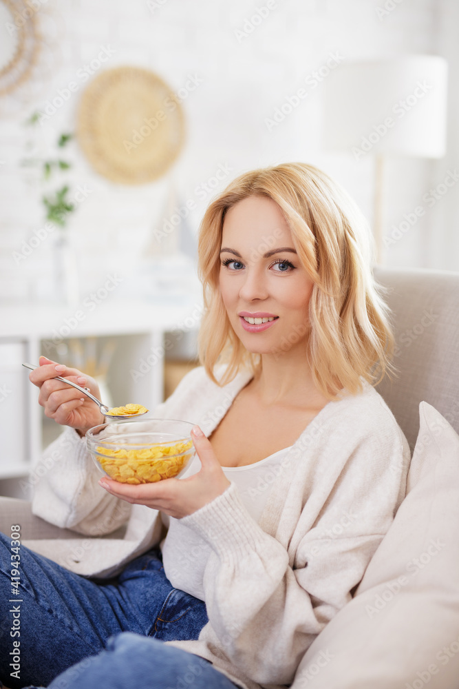 healthy food and breakfast concept - young beautiful woman eating corn flakes