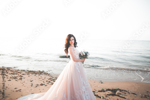 Romantic beautiful bride in white dress posing on the background sea