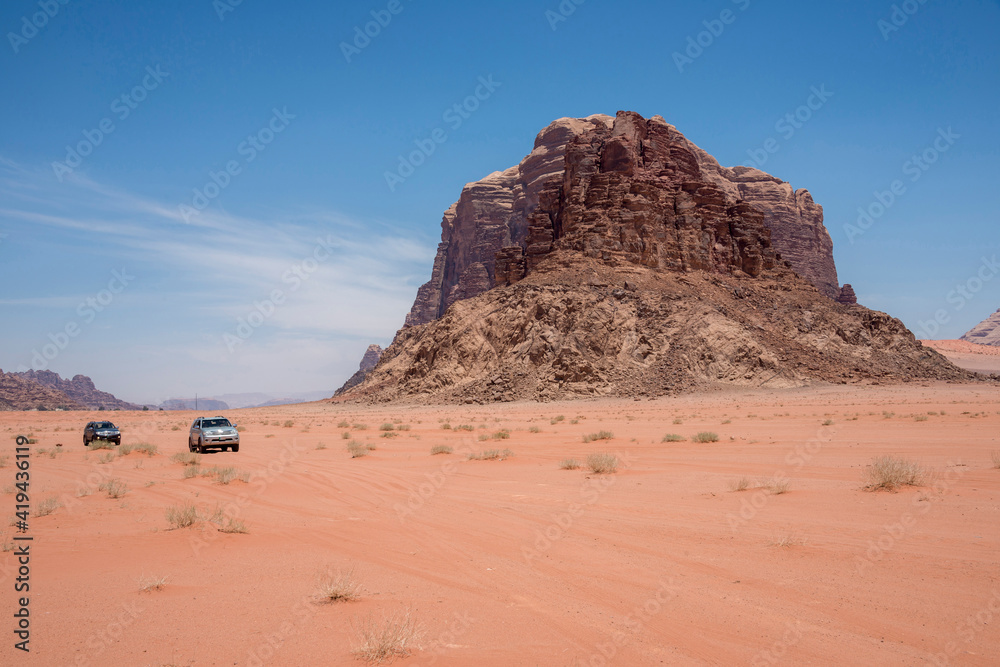 Paisaje con vehículos y la montaña de los Siete Pilares en el desierto de Wadi Rum de Jordania Paisaje con vehículos y la montaña de los Siete Pilares en el desierto de Wadi Rum de Jordania