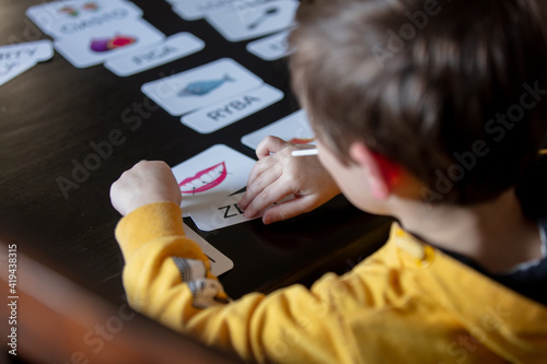 little boy learns words from cards under the ABA therapy program at home at the table photo