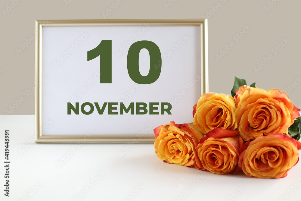 Fototapeta premium day of the month 10 November calendar photo frame and yellow rose on a white table