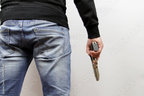 Back view killer holding hand gun. Man wearing blue jeans.