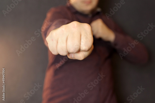 male hand shows fist close up on dark background