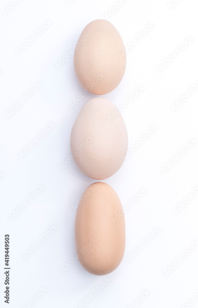 Three beige eggs in vertical position on white background, indian file Three beige eggs in vertical position on white background, indian file