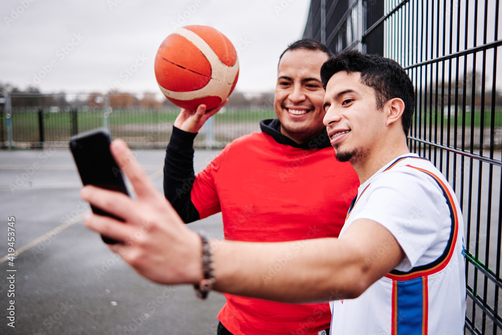 Two latino friends taking a selfie at the court after playing a basketball game. Two latino friends taking a selfie at the court after playing a basketball game.