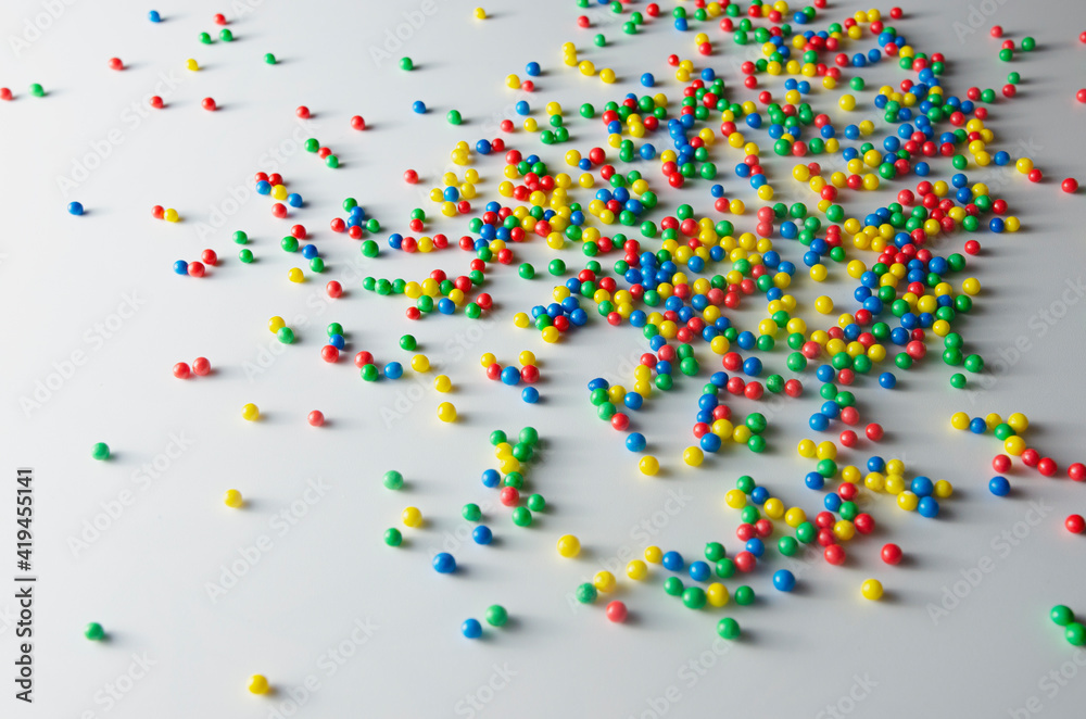 Multicolored balls of candy are randomly scattered on a white background