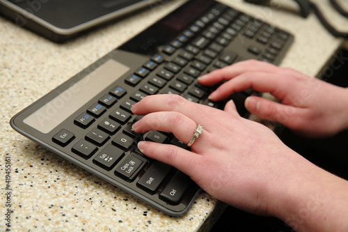 woman's hands typing on modern keyboard in office environment