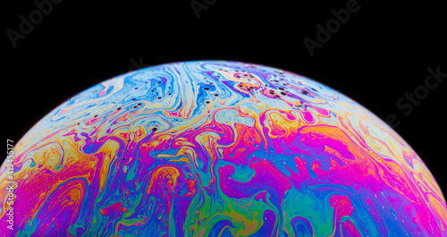 Panoramic view of closeup bubble textured backdrop representing colorful planet with wavy lines on round shaped surface on black background photo