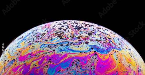 Panoramic view of closeup bubble textured backdrop representing colorful planet with wavy lines on round shaped surface on black background
