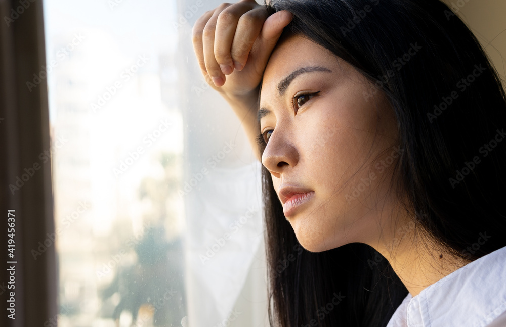 Side view of young ethnic female executive looking away against window in workspace Side view of young ethnic female executive looking away against window in workspace