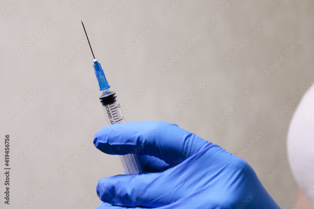 A doctor in medical gloves holds a syringe and a vaccine. Syringe with a vaccine. An injection from diseases. A doctor in medical gloves holds a syringe and a vaccine. Syringe with a vaccine. An injection from diseases.