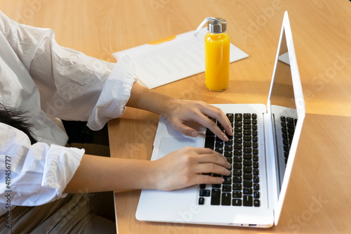 crop female entrepreneur browsing netbook while sitting with paper document and eco friendly glass bottle of fresh juice photo