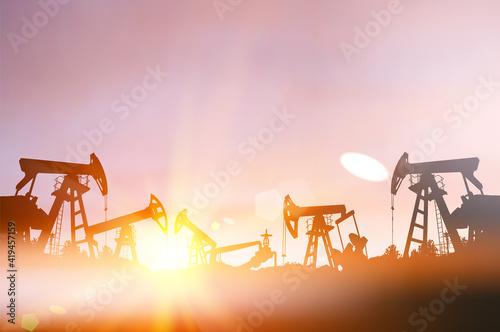 Darck silhoutte of oil rig and pumps during sunset.