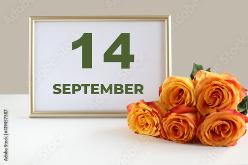 day of the month 14 September calendar photo frame and yellow rose on a white table