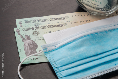 Tableau sur toile US economic stimulus checks with dollar bills in the background with a facemask