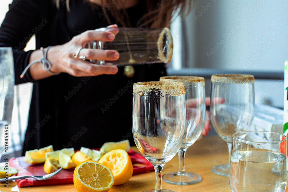Woman applying sugar rim on glasses at table