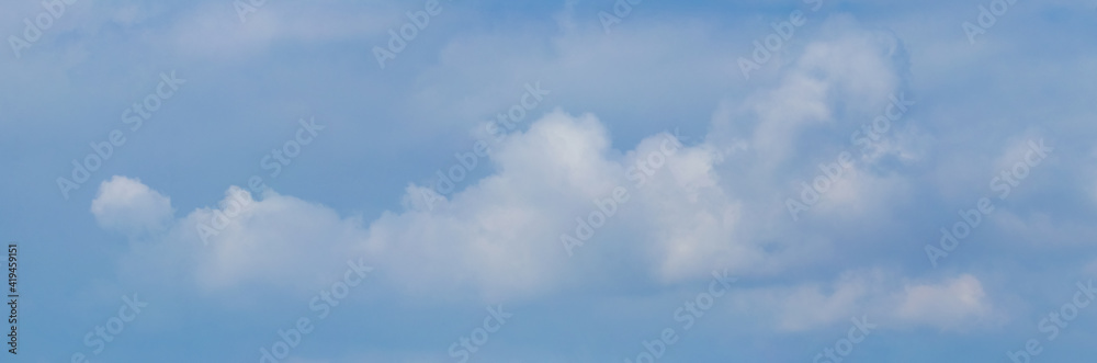 Panorama of blue cloudy sky with white fuzzy clouds