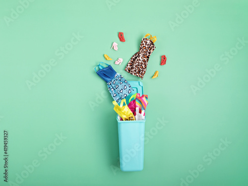 Dresses and shoes in trash bin. Mass fashion, recycling, ethical consumption idea