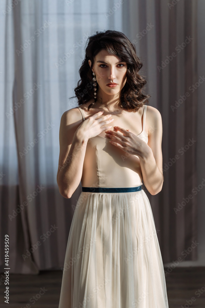 Cute young girl stands in the studio on the background of curtains. A stern look straight into the camera. Cute young girl stands in the studio on the background of curtains. A stern look straight into the camera.