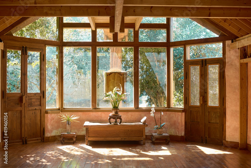 Interior of spacious meditation hall in house with potted plants and parquet in daytime photo