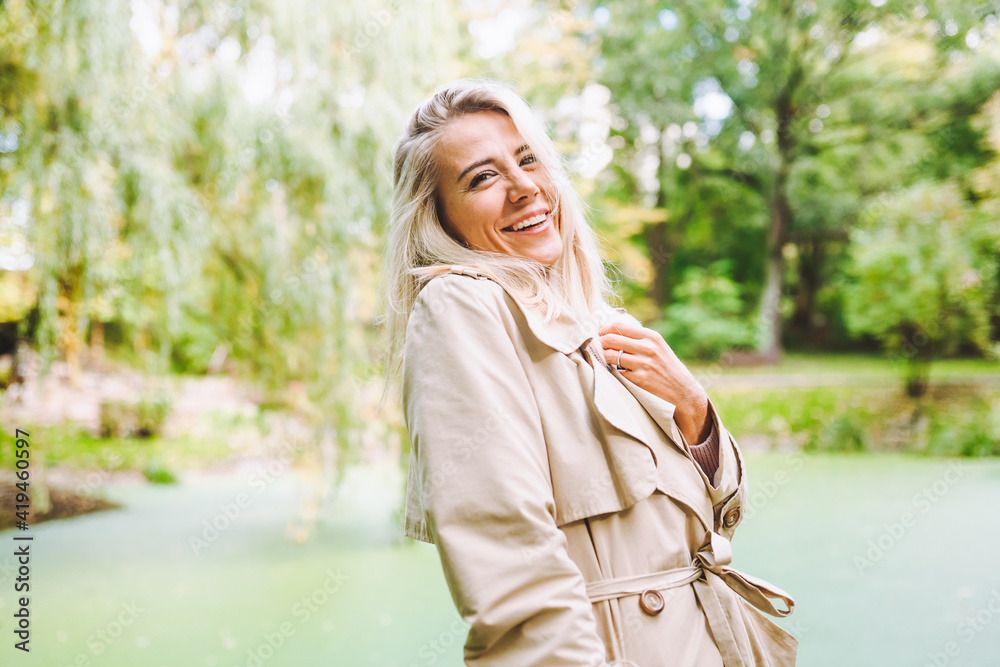 Caucasian blonde woman smiling happily on sunny summer or spring day outside walking in park. Caucasian blonde woman smiling happily on sunny summer or spring day outside walking in park.
