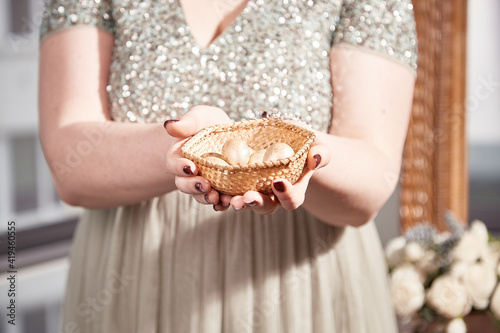 Beautiful girl holds a small basket with golden quail eggs. Happy Easter