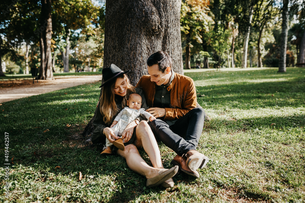 Loving young parents with cute infant child enjoying summer weekend together in green park Loving young parents with cute infant child enjoying summer weekend together in green park