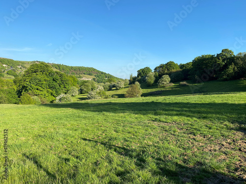 Long shadow  stretching over the fields  with trees and hills in the distance in  Shibden Valley  Halifax  UK