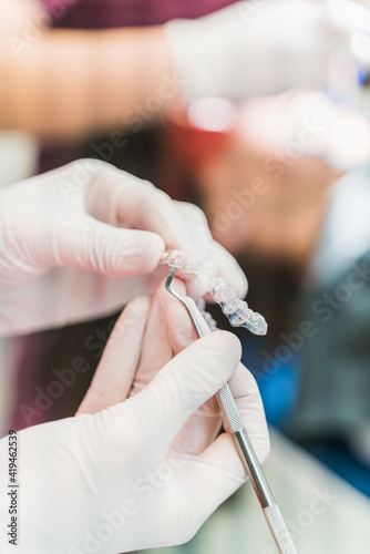 Crop unrecognizable dentist in latex gloves holding ultra thin veneers and scaler while working in dental clinic photo