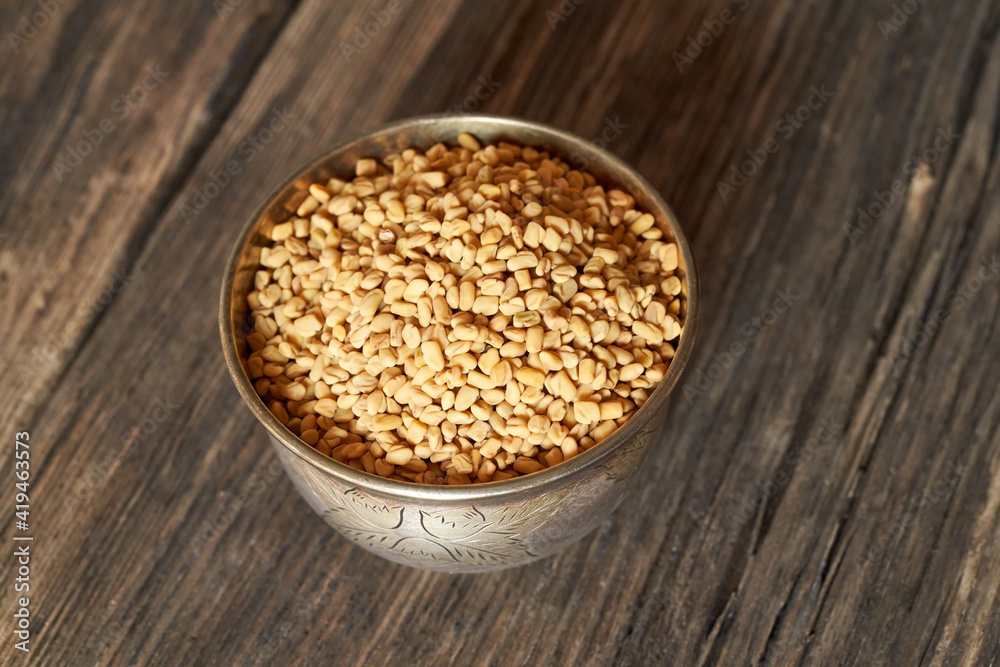 Fenugreek seeds in a bowl on a wooden table Fenugreek seeds in a bowl on a wooden table