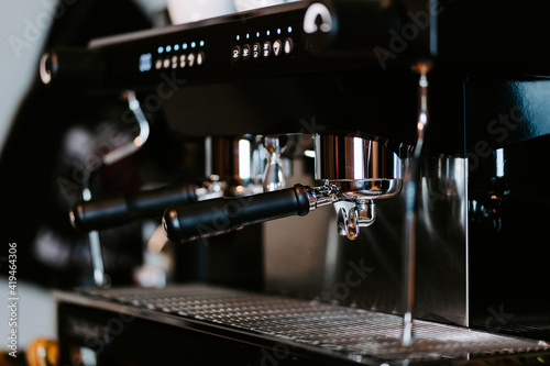 Shiny metal portafilters in contemporary coffee maker placed on counter in coffee shop photo