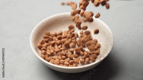 Feed for animals poured into a bowl on a gray table. Slow-motion