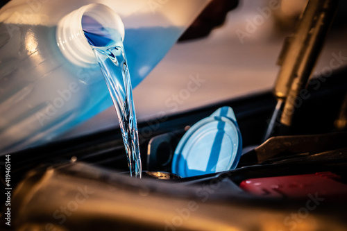 Pouring blue antifreeze liquid for washing car screen. photo