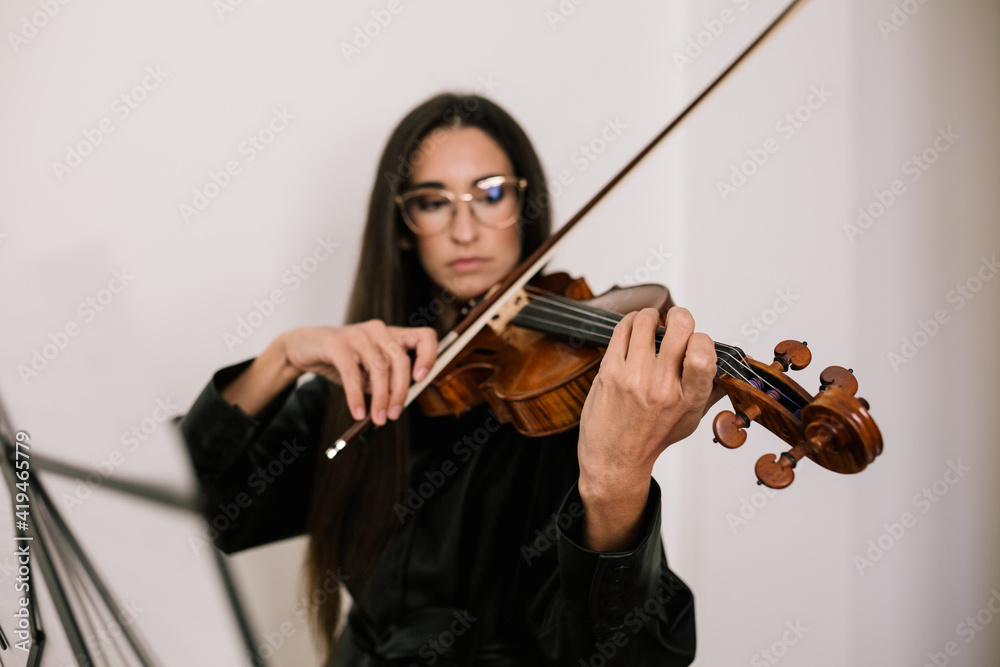 Serious artist playing stringed musical instrument while practicing skills standing against white background Serious artist playing stringed musical instrument while practicing skills standing against white background