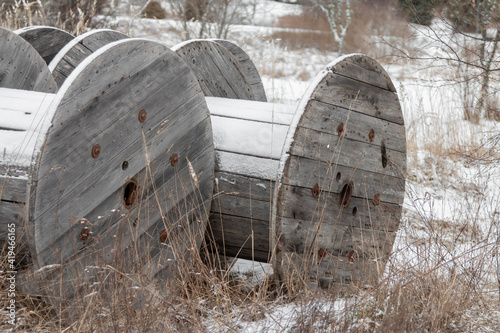 Old cable wooden coils stand in the meadow during the winter