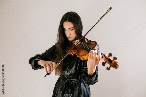 Serious artist playing stringed musical instrument while practicing skills standing against white background