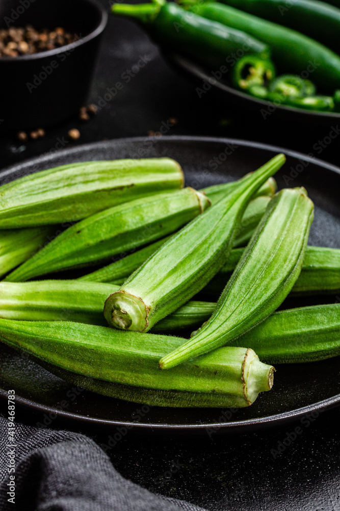 Top view of ripe green superfood on ceramic black plates near pepper in bowl on table
