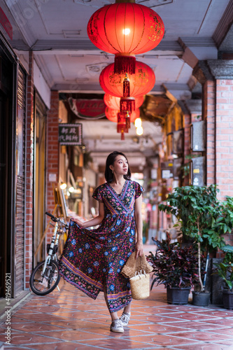 Young Asian female in long dress walking along historic Daxi Old Street and looking away while enjoying vacation in Taiwan photo