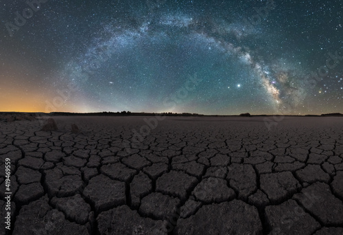 Drought cracked lifeless ground arid terrain with starry sky at night photo