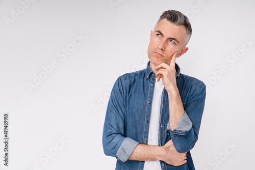 Pensive mature caucasian man in denim shirt isolated in white background
