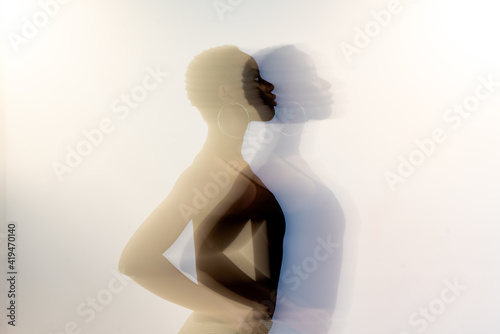 Double exposure of slim black female with short hair holding hands on waist against gray background photo