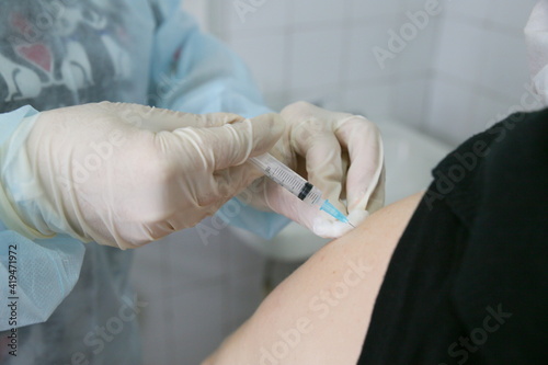 The doctor injects the patient with the vaccine against COVID-19