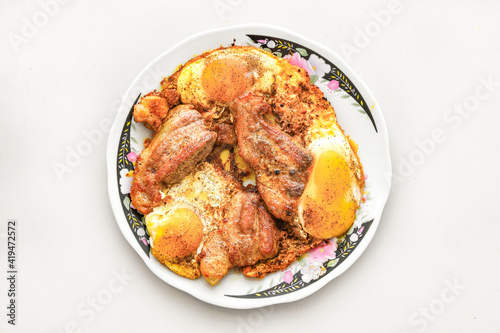 Pieces of fried meat cooked with scrambled eggs in a pan.