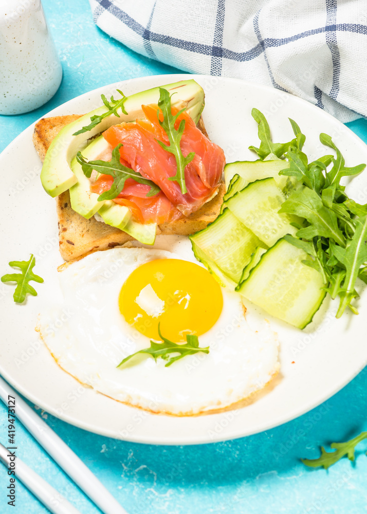 Breakfast. Fried egg, toast with salmon and avocado and fresh salad.