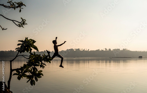  A young male enjoying a summer splash into San Pablo lake in the Philippines. The Mt. Banahaw can be seen on the background on this early morning summer.