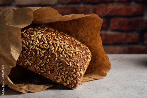 Tasty whole bread with brown crust and sunflower seeds on top on table in daylight photo