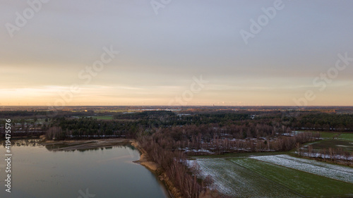 Aerial view of a beautiful and dramatic sunset over a forest lake reflected in the water, landscape drone shot. Blakheide, Beerse, Belgium. High quality photo © Bjorn B