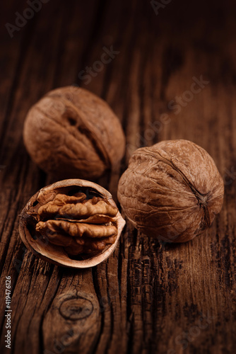 Obraz na płótnie Three ripe walnuts on textured wood brown background. Closeup. Selective focus. w salonie