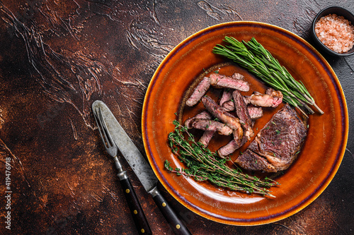 Grilled sliced rib eye or ribeye beef meat steak on a rustic plate. Dark background. Top view. Copy space