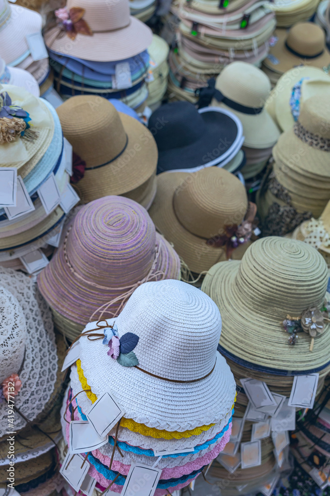 A variety of trendy and colorful hats on the counter of the store. Women's sun hats of different colors